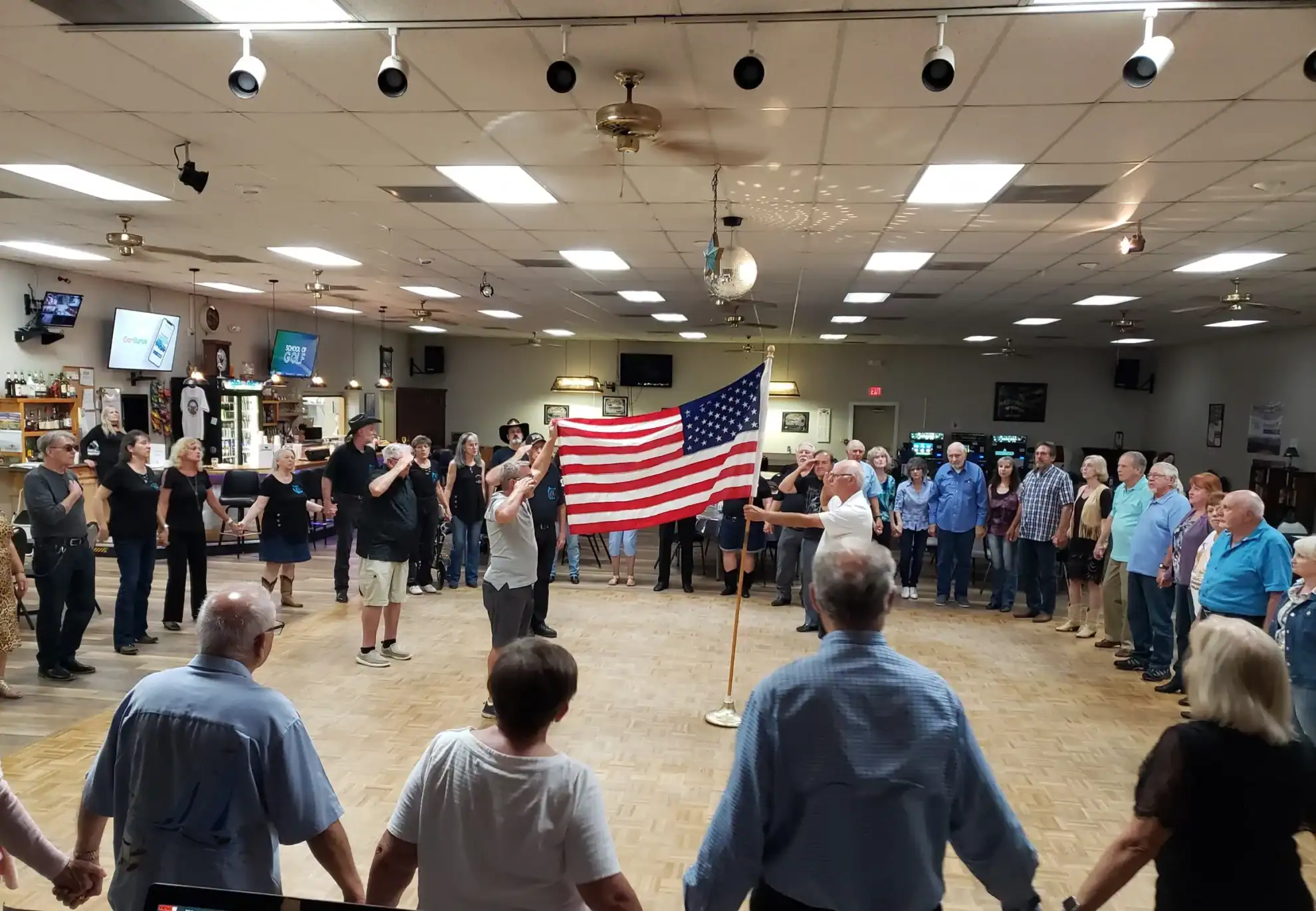 Line dancers facing the American flag in the Elks Lodge 2582 hall